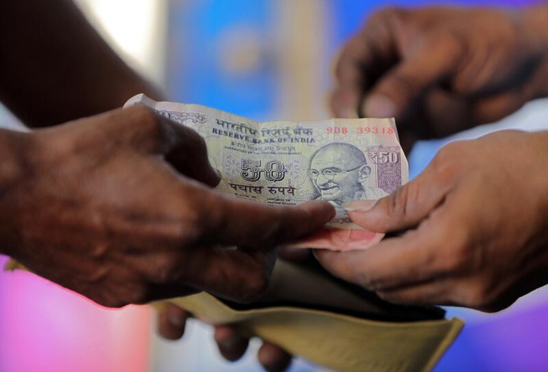 A customer hands a 50-Indian rupee note to an attendant at a fuel station in Ahmedabad, India, October 5, 2018. REUTERS/Amit Dave