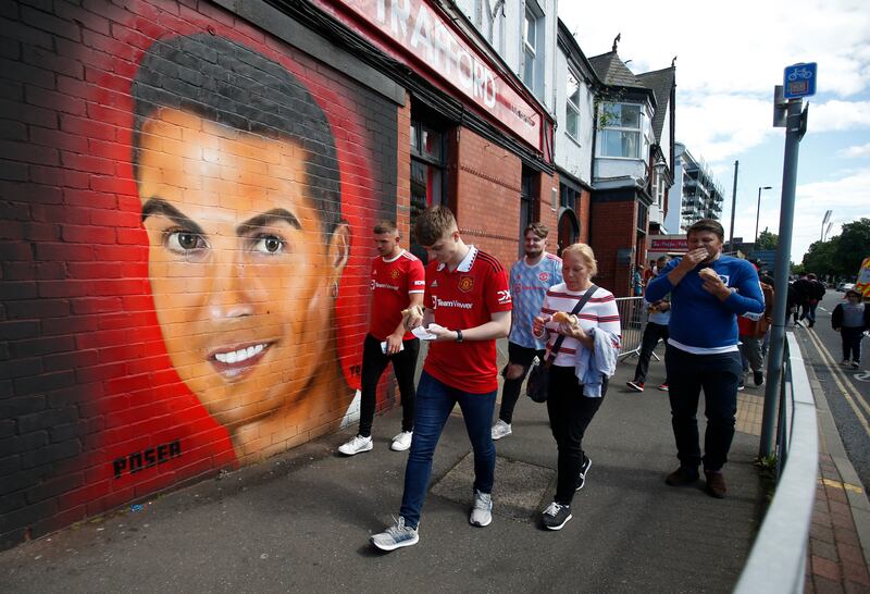 Fans walk past a mural of Manchester United's Cristiano Ronaldo at Old Trafford. Reuters