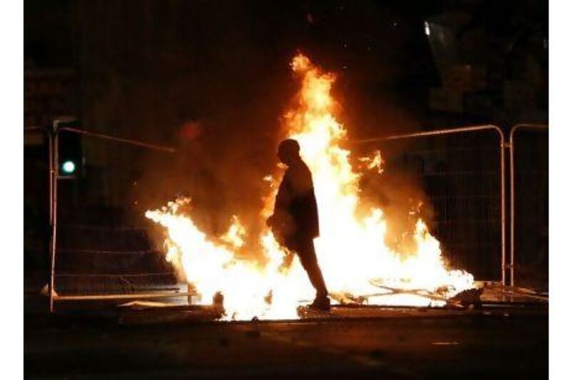 A rioter walks past a burning barricade in the city of Liverpool, one of several UK centres to which rioting has spread. A letter-writer says firm measures are needed to halt the disorder. Phil Noble / Reuters