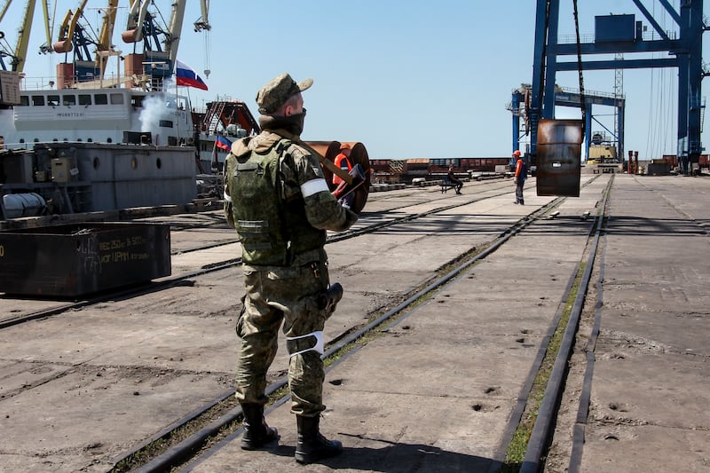 A Russian soldier oversees the loading of steel on to a Russian ship at Mariupol port in Ukraine. AP