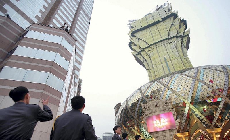 Visitors admire the new Grand Lisboa hotel and casino (R) ahead of the casino's official opening in Macau, 11 February 2007.  Billionaire tycoon Stanley Ho, who for 40 years held a monopoly on gambling in the southern Chinese territory and has seen his market share of the business slide with the opening since 2004 of rival Las Vegas-style casinos, launched his comeback campaign in Macau by opening a huge casino 11 February he hopes will bring punters back to his once-dominant gaming halls.     AFP PHOTO/Samantha SIN (Photo by SAMANTHA SIN / AFP)
