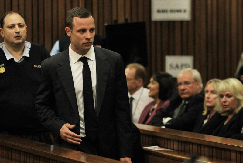 South African Paralympic athlete Oscar Pistorius passes the mother of his late girlfriend, June Steenkamp, second from right, as he arrives in court for the start of his murder trial on March 3, 2014. Themba Hadebe / EPA