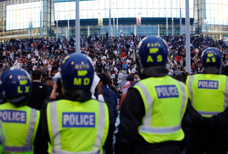 A line of police watch supporters outside Wembley Stadium ahead of the Euro 2020 final between Italy and England. AP
