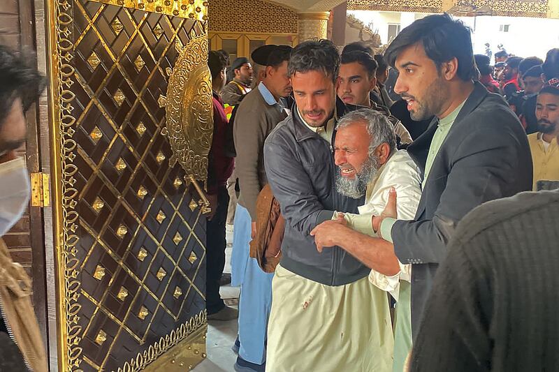People help and console an elderly man after the blast at the mosque. AFP  