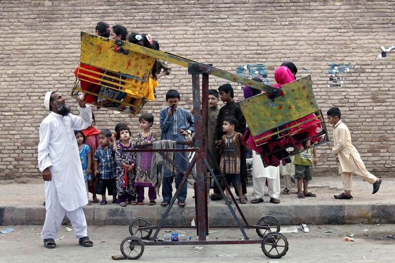 Pakistani children ride a seesaw in Peshawar. Bilawal Arbab / EPA