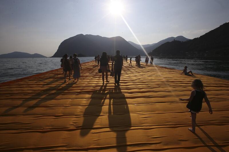 Jiwon Shin, left, and Khalid Altamini cast a shadow as the walk on the installation entitled The Floating Piers at the Iseo Lake. Luca Bruno / AP photo