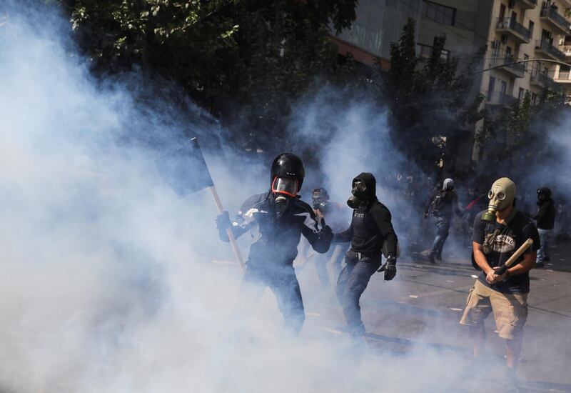 Protesters are seen shrouded in  tear gas during clashes outside the court in Athens. Reuters