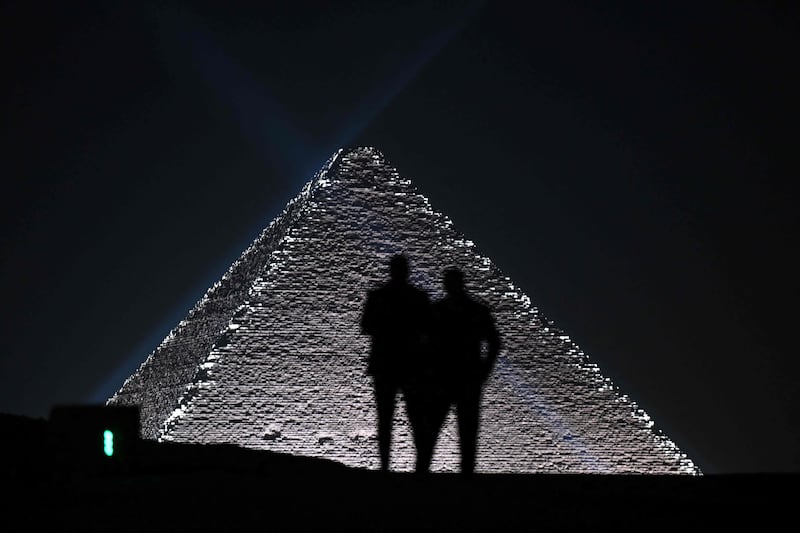 Models are silhouetted against the pyramids. AFP