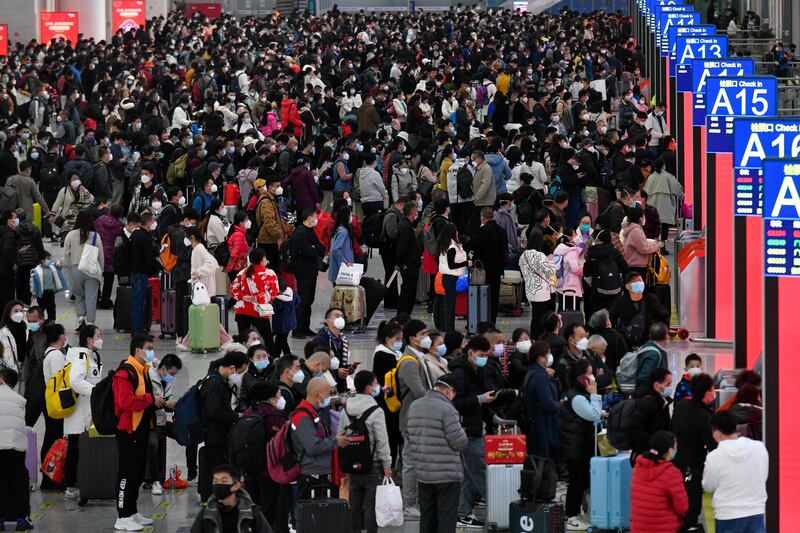 People wearing masks prepare to catch their trains at the North Railway Station in Shenzhen, a city in southern China's Guangdong province. Xinhua via AP