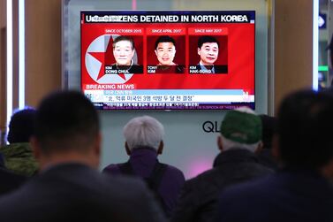 People watch a TV news report screen showing portraits of three Americans, Kim Dong Chul, left, Tony Kim and Kim Hak Song, right, detained in the North Korea, at the Seoul Railway Station in Seoul. Ahn Young-joon / AP
