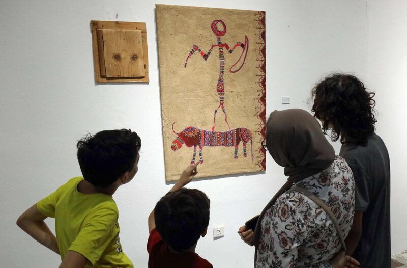 Libyans look at a painting by artist Elham el-Ferjani at the Hamim Gallery in the eastern city of Benghazi. The eastern Libyan city is hosting a rare week of culture featuring theatre, music, cinema and art, as the country attempts to turn the page on a decade of violence. AFP