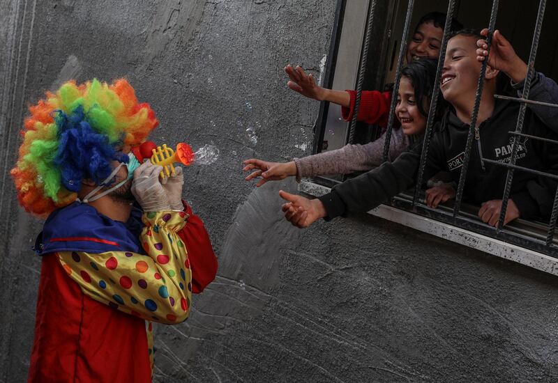 A Palestinian clown wears a protective face mask while entertaining children staying at their home due a precautionary measure against the spread of the coronavirus, in Khanyounis refugee camp, southern Gaza Strip.  EPA