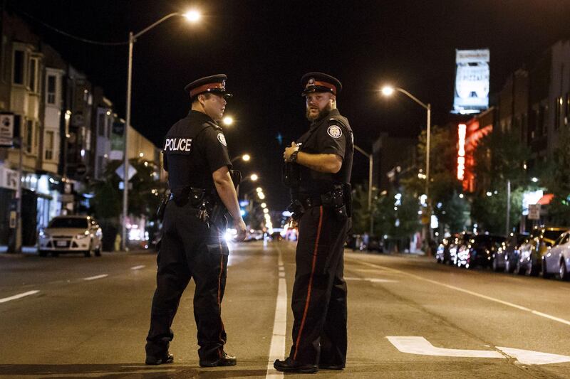 Toronto Police Officers stand watch at the foot of Danforth St. at the scene of a shooting in Toronto. AFP