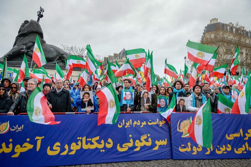 People hold a banner and wave former Iranian flags during a demonstration of the exiled Iranian opposition to protest against the celebration in Iran of the 40th anniversary of the Islamic Revolution, on February 8, 2019 in Paris. / AFP / -
