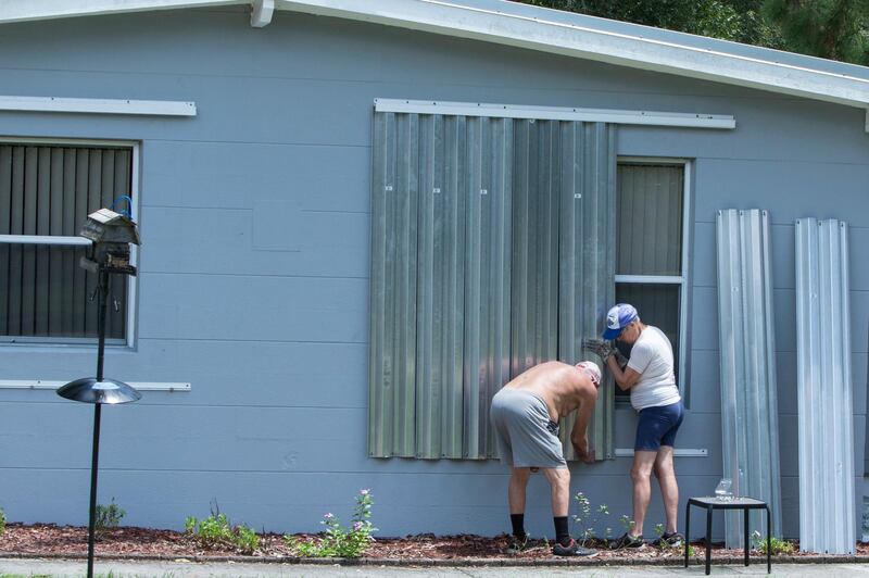 James Wolfe, 72, left, and Elaine Wolfe, 65, install shutters on their home in Vero Beach. AP Photo