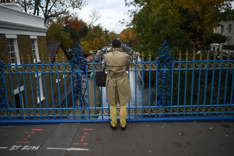 A man is seen taking a photo of autumnal trees along the canal in Little Venice. Getty Images