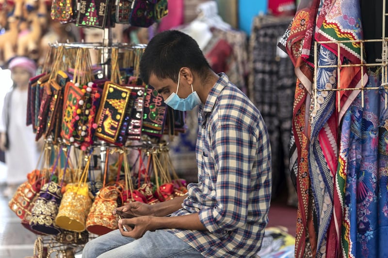 DUBAI, UNITED ARAB EMIRATES. 15 JUNE 2020. STANDALONE. Bur Dubai life during COVID-19.  A man selling souvenirs browses his phine while wearing a face mask as he waits for potential clients. (Photo: Antonie Robertson/The National) Journalist: None. Section: National.