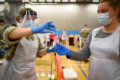 MERTHYR TYDFIL, WALES - NOVEMBER 24: An RAF airwoman hands over a used swab test to a volunteer health worker at a temporary COVID-19 testing site within a leisure centre on November 24, 2020 in Merthyr Tydfil, Wales. The British Armed Forces have deployed around 170 RAF personnel to support mass testing in Merthyr Tydfil and surrounding areas in South Wales. The personnel are helping to run mass testing sites around the town and are using lateral flow tests to help identify asymptomatic cases and break chains of transmission. South Wales is currently the region of the country hardest hit by the COVID-19 pandemic, with Merthyr Tydfil recently named as having the worst case rate for Covid-19 in the UK. (Photo by Leon Neal/Getty Images)