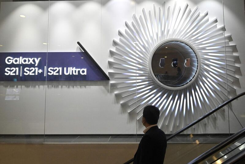 A man steps down the stairs in front of an advertisement for the Samsung Galaxy S21 smartphone at the company's showroom in Seoul on April 7, 2021. / AFP / Jung Yeon-je
