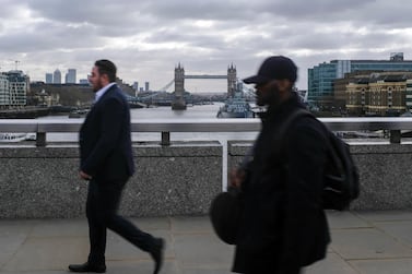 People commute across London Bridge, in London, with Tower Bridge in background. AP 