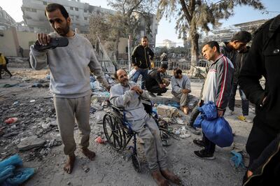 A man sits in a wheelchair as Palestinians inspect the damage at Al Shifa Hospital. Reuters