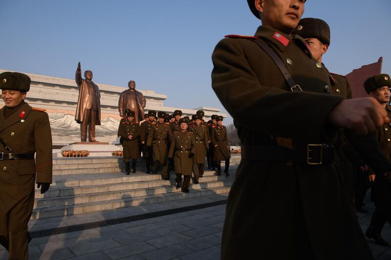 Korean People's Army soldiers leave the statues of Kim Il Sung and Kim Jong Il. AFP