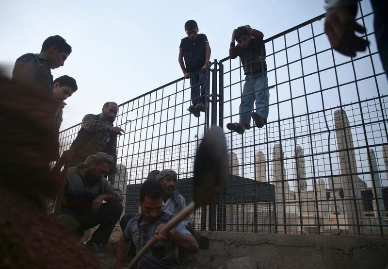 Boys watch men digging a grave for 15-year-old Ziad Rihani, who was killed during shelling, ahead of his burial in a graveyard in the rebel held besieged Douma neighbourhood of Damascus, Syria. Bassam Khabieh / Reuters