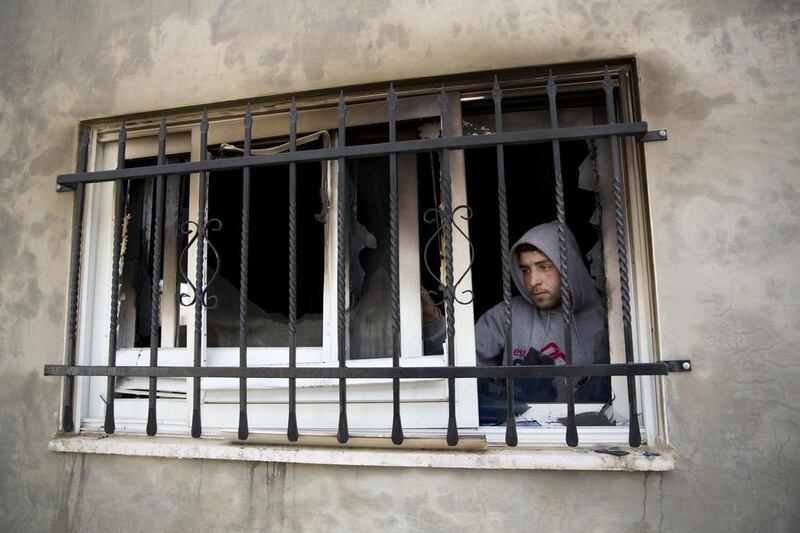 A Palestinian man looks out a window in a house that was torched in the Palestinian village of Duma near the West Bank city of Nablus, this month. Majdi Mohammed / AP Photo