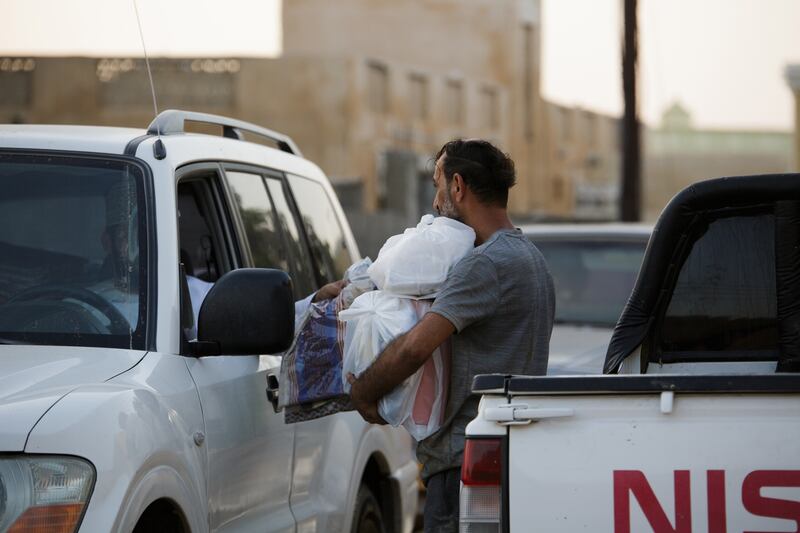 A resident receives handouts, food and clothes, from a motorist in Qasbit Al Zaab.