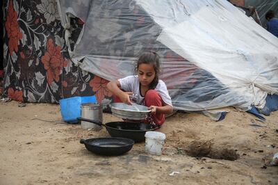 A girl pours water next to a tent in Rafah. Reuters