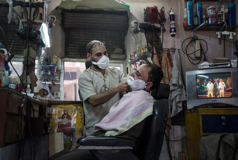 epa08428136 A barber wear a face mask during a civil initiative to sterilize garbage collectors' neighborhood of 'The Zebaalin' to help stop the spread of coronavirus at Cairo, Egypt, 17 May 2020.  EPA/Mohamed Hossam