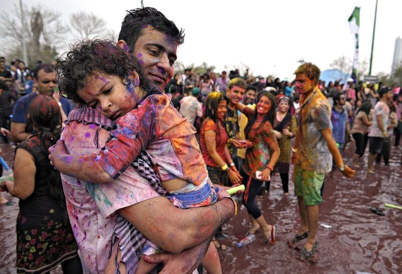 A father holds his tired daughter as a crowd of hundreds celebrates the Hindu festival of Holi during Rang de 2014 by rubbing chalk on themselves and others, dancing and splashing water at Wonderland Park. Jeff Topping / The National / March 14, 2014