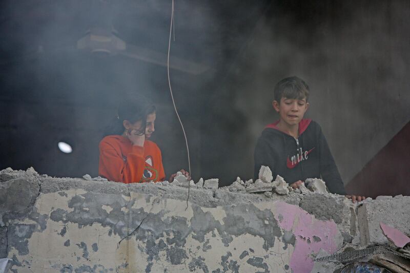Syrian children watch the aftermath from their damaged balcony. AFP