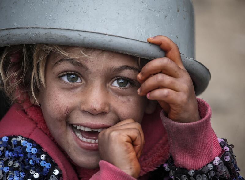 A Palestinian girl waits with her pot to receive free food from Amel Abu Amra, a woman who collects food donations to cook for the disadvantaged, in the east of Gaza City. EPA