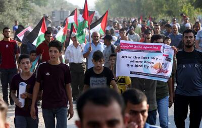 Demonstrators march with placards during a protest at the Palestinians side of Erez border crossing between Gaza and Israel, in Beit Hanoun, northern Gaza Strip, Tuesday, Sept. 4, 2018. The Health Ministry in Gaza says several Palestinians were wounded by Israeli fire as they protested near the territory's main personnel crossing with Israel. (AP Photo/Adel Hana)