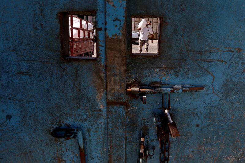 A worker is seen through an opening in a school door as he carries a sack of flour distributed by UNRWA to be delivered to a Palestinian family amid the coronavirus outbreak, in Gaza City. Reuters