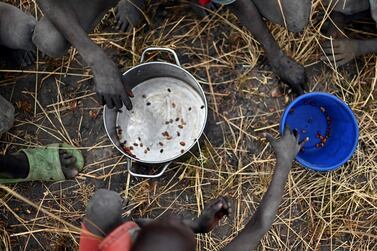 Children collect spilt grain following a World Food Programme food drop in Ayod county, South Sudan, February 6, 2020.  AFP 