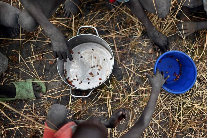 (FILES) In this file photo taken on February 6, 2020 children collect grain spilt on the field from gunny bags that ruptured upon ground impact following a food drop from a plane at a village in Ayod county, South Sudan, where World Food Programme (WFP) have just carried out a food drop of grain and supplementary aid. The UN appealed on December 1, 2020  for a record $35 billion to provide aid in 2021, as the pandemic left tens of millions more people in crisis, and with the risk of multiple famines looming. The world body's annual Global Humanitarian Overview estimated that 235 million people worldwide will need some form of emergency assistance next year -- a staggering 40-percent increase in the past year.
 / AFP / TONY KARUMBA
