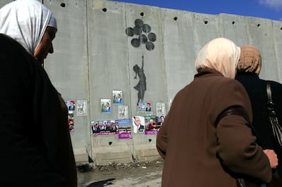 Palestinian women pass graffiti by the British artist Banksy on Israel's separation wall near the Israeli army's Qalandia checkpoint, between Jerusalem and Ramallah in the West Bank. Getty Images