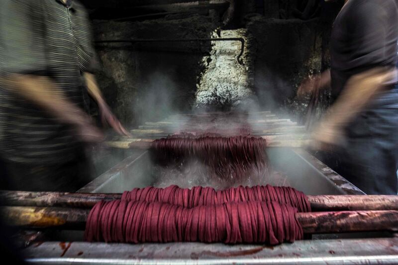 Workers spin dyed yarns from a vat at a traditional hand-dying workshop in the Egyptian capital Cairo's centuries old district of Darb al-Ahmar. AFP