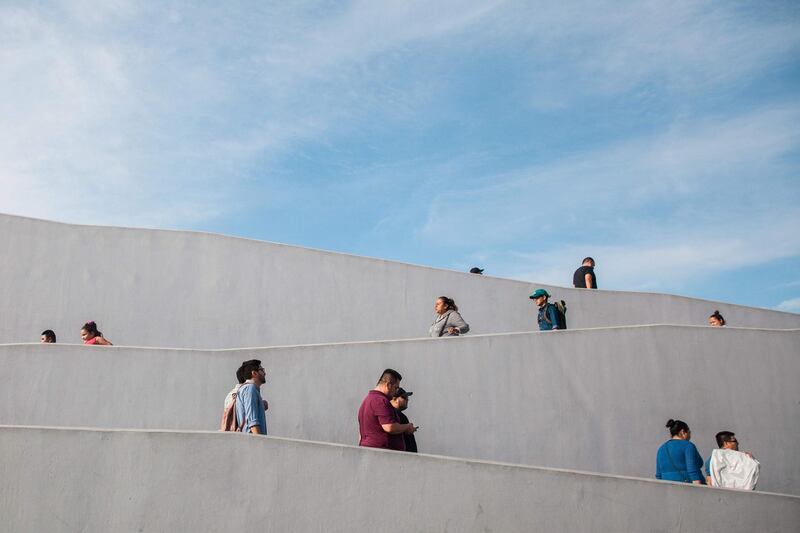 People walk down a pathway at the El Chapararl border crossing in Tijuana, Mexico. AFP