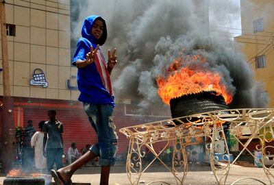A Sudanese protester gestures as he walks past burning tyre near Khartoum's army headquarters on June 3, 2019 after security forces broke up a weeks-long sit-in. General Abdel Fattah al-Burhan, interim leader of Sudan where security forces broke up a weeks-long sit-in in a deadly operation Monday, was largely unknown until seven weeks ago. A doctors' committee said at least 13 people were killed as gunfire echoed from the protest site outside army headquarters in central Khartoum.
 / AFP / Ebrahim Hamid
