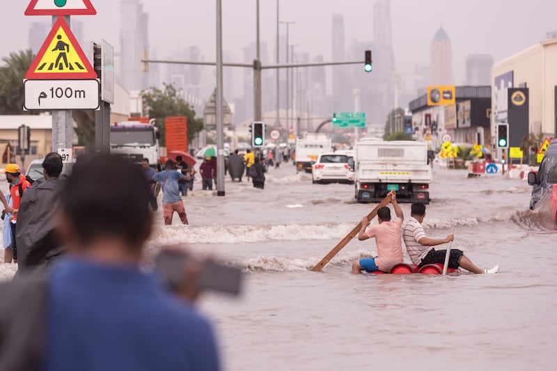 Two men navigate Dubai's flooded roads on a raft made from gas cylinders. Antonie Robertson / The National