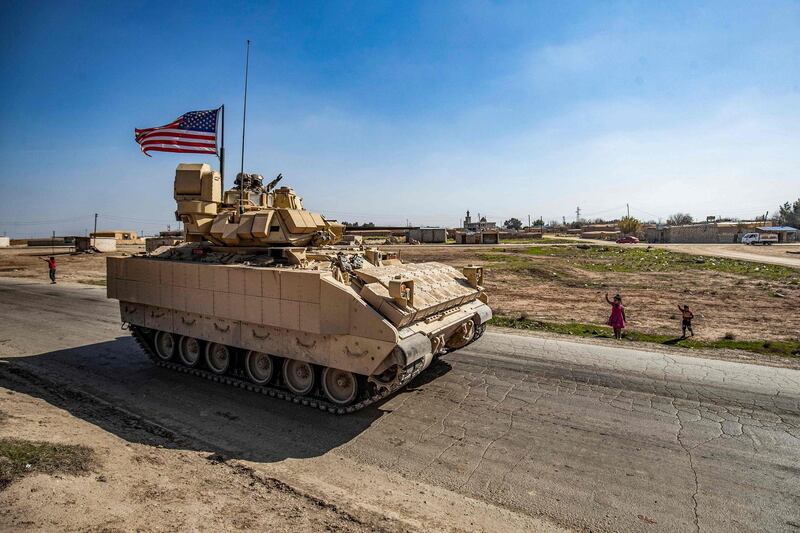 US soldiers on a Bradley Fighting Vehicle (BFV) wave to children on the side of the road during a patrol in the Suwaydiyah oil fields in Syria's northeastern Hasakah province on February 13, 2021.  / AFP / Delil SOULEIMAN
