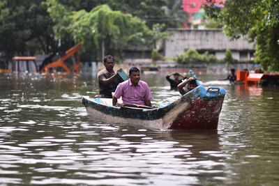People use a boat to cross a flooded road following heavy downpour during Cyclone Michaung in Chennai, India. EPA
