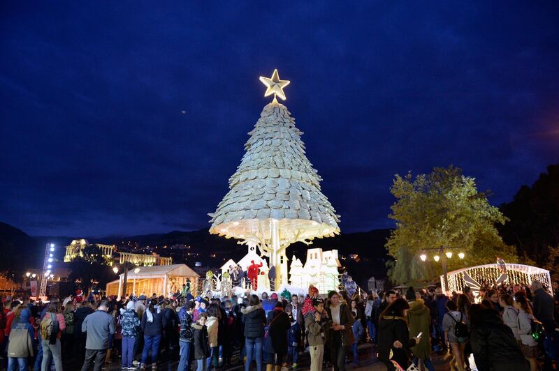 People gather near the 30-metre-high Christmas tree which has been officially lit up at the entrance of Bnachii Lake, Zgharta district, north Lebanon. EPA