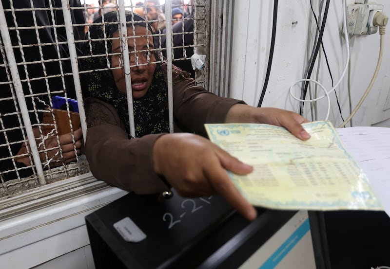 A Palestinian woman presents her ration card to receive food. Reuters
