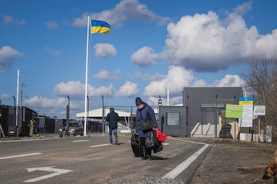 A woman walks from Russia-backed separatists territory into Ukraine as a senior British official warns that the invasion has "already begun in effect" with false flag operations. AP