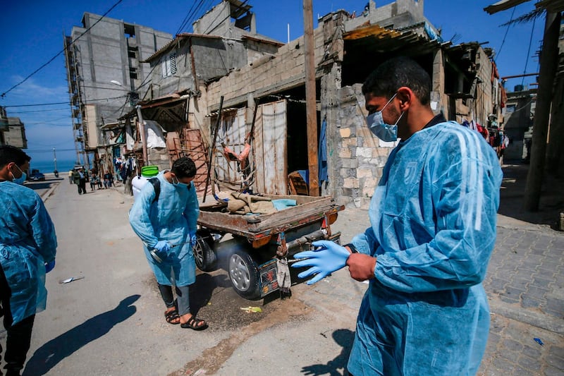 Palestinian volunteers sprays disinfectant a street at Al Shati refugee camp in Gaza City . AFP