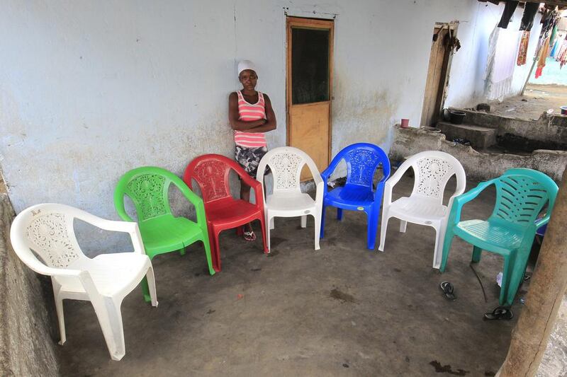 Musu L Kromah poses for a family portrait at her home in West Point, Monrovia, Liberia. The empty chairs are a representation of Musu’s parents and five other family members who died of the Ebola virus during an outbreak of the disease in 2014. Ahmed Jallanzo / EPA